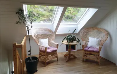 two wicker chairs and a table in a room with two windows at Cozy Apartment In Fitjar in Fitjar
