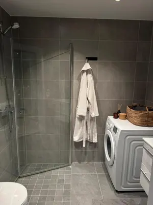 a bathroom with a shower and a washing machine at LADE - leilighet i Ringve Pluss in Trondheim