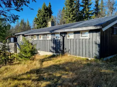 a building with a garage with trees in the background at Traditional Family Cabin Near Rabalen in Bagn
