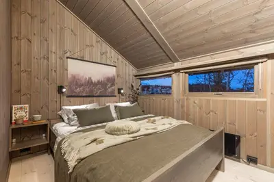 a bedroom with a large bed in a room with wooden walls at Hedda Hedalsfjellet - 3 bedroom cabin with a lovely view in Hedalen
