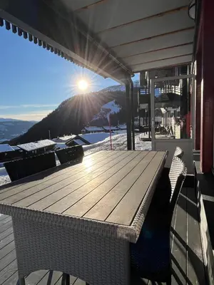 a wooden table and chairs on a deck with the sun shining at Mountain Sauna Lodge - Private Sunset Deck in Vossevangen