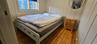 a bed in a small room with a window at Fjellheimens Svanebu in Tyinkrysset