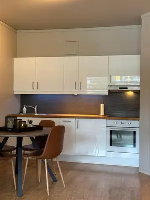 a kitchen with white cabinets and a table and chairs at Geiloholtet central city apartment in Geilo