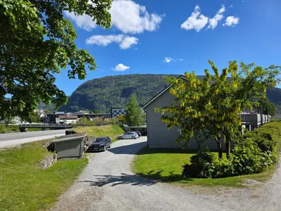 a house on the side of a road with a tree at Rom 3 i bufellesskap in Sogndal
