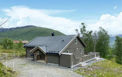 a house with a garage with a mountain in the background at Cozy Home In Hornindal With Sauna in Hornindal