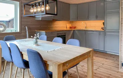 a kitchen with a wooden table and blue chairs at Cozy Home In Hornindal With Sauna in Hornindal