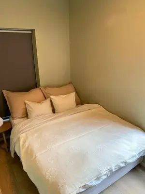 a bed with white sheets and pillows in a room at Familyhome for 8 people - 4 bedrooms - 10min from Bergen city center in Bergen