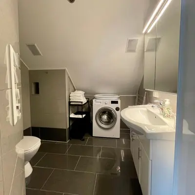 a bathroom with a washing machine and a sink at Private room with a view and garden - 12 min from the city center in Bergen