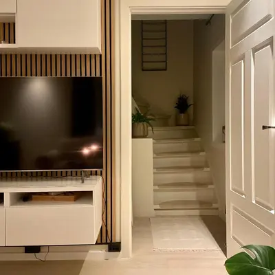 a living room with a television and a staircase at Private room with a view and garden - 12 min from the city center in Bergen