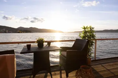 a table and chairs on a deck with a view of the water at Heimby Homes - Seaside Balcony Stay in Bergen