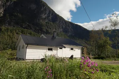 a white building in front of a mountain at Hansali Holiday Home in Fjarland