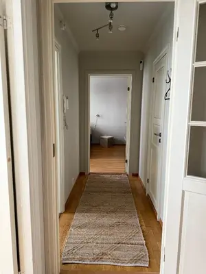 an empty hallway with a rug on the floor at Romslig leilighet midt i Bergen sentrum - komfort med kvalitetsenger og dyner in Bergen