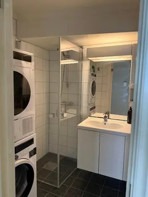 a bathroom with a sink and a washer and dryer at Romslig leilighet midt i Bergen sentrum - komfort med kvalitetsenger og dyner in Bergen