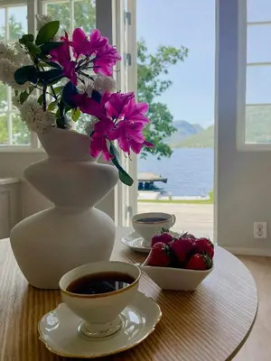 a table with a vase with flowers and a cup of coffee at Renovated 1918 House By The Sea In Sandeid in Sandeid
