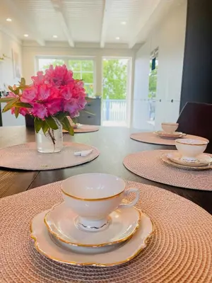 a table with plates and a vase of pink flowers at Renovated 1918 House By The Sea In Sandeid in Sandeid
