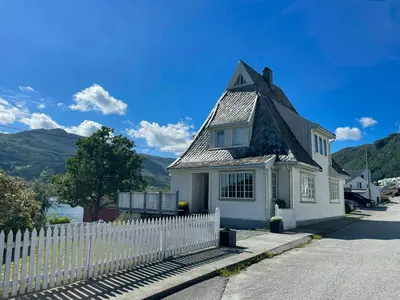 a white house with a white picket fence at Renovated 1918 House By The Sea In Sandeid in Sandeid