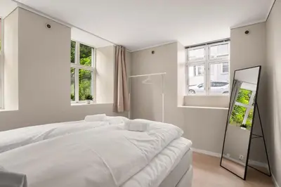 a white bedroom with a large bed and two windows at City Apartment I Short Walk to Sights in Bergen