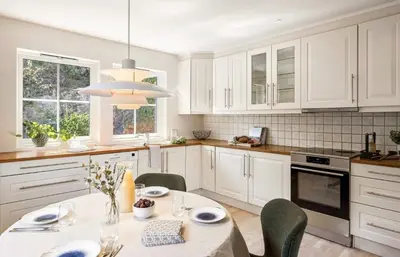 a kitchen with white cabinets and a table with chairs at Sentrumsnær bolig in Lii