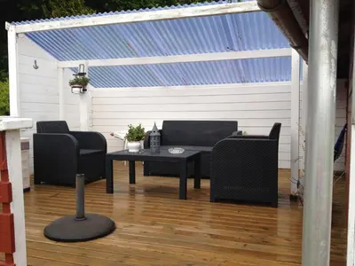 a patio with a table and chairs on a wooden floor at Two floors house with 3 bed rooms and room for 8 persons in Ålesund