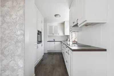 a white kitchen with white cabinets and wooden floors at Family & Friends Space in Råholt in Lii