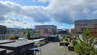 a rooftop patio with tables and chairs and buildings at Cozy apartment Trondheim, free parking in the basement in Trondheim