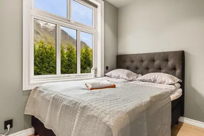 a bedroom with a large bed with a large window at Hardanger Odda Apartments in Odda