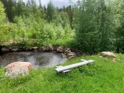 a bench sitting in the grass next to a pond at Beautiful place among forests and fields in a good old style in Eggedal