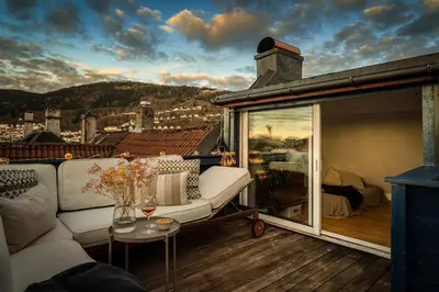 a balcony with a couch and a view of a city at Penthouse apartment in the heart of Bergen with beautiful private rooftop in Bergen