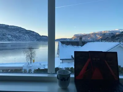 a laptop sitting on a window sill with a view of snow at The View in Sauda