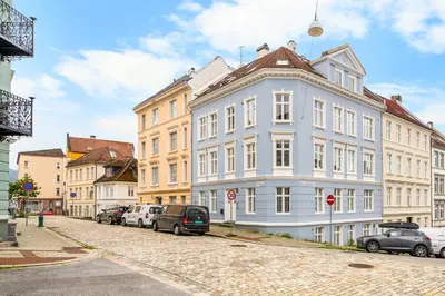a large white building on a street with parked cars at Central & Modern Apartment in the Coziest Street in Bergen in Bergen