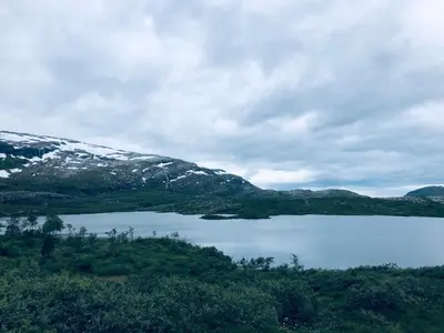 a body of water with a snow covered mountain at Familiehytte på Kvamskogen in Kvam