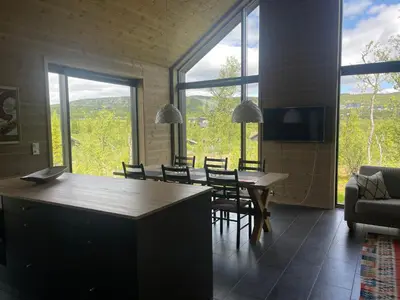 a living room with a table and chairs and a large window at The Lookout at Beitostølen in Beitostøl