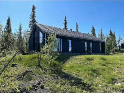 a black house in the middle of a field at The Lookout at Beitostølen in Beitostøl