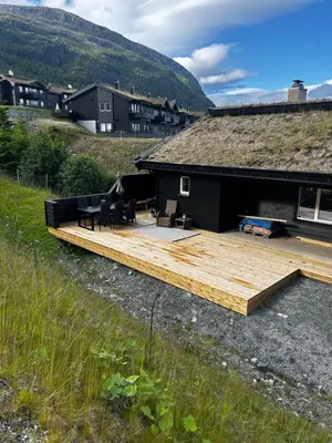 a house with a wooden deck in a field at Flott leilighet på Voss i Tråstølsvegen med 3 soverom 6 sengeplasser in Skulestadmo