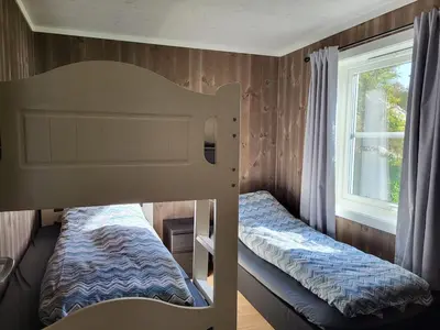 a bedroom with a bunk bed and a window at Hytte ved sjøen in Røyra