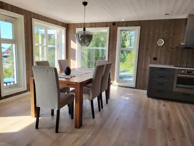 a dining room with a wooden table and chairs at Hytte ved sjøen in Røyra