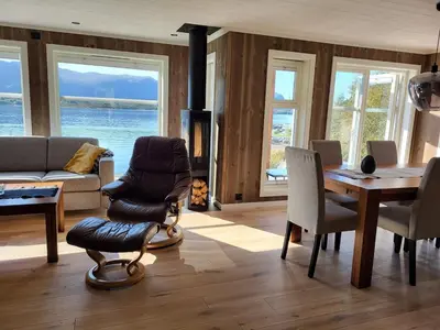 a living room with a table and chairs and a fireplace at Hytte ved sjøen in Røyra