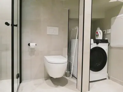 a bathroom with a toilet and a washing machine at Aurum Bergen Apartment in Bergen