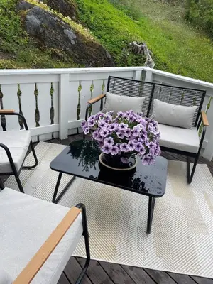 a patio with a table with purple flowers on it at Trivelig lite hus in Lii