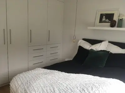 a bedroom with a bed and a white cabinet at Lys leilighet på Kaldnes in Lii