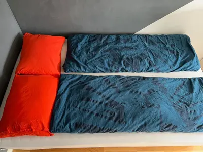 a bed with blue comforter and two red pillows at Family-friendly townhouse on Landås in Lii