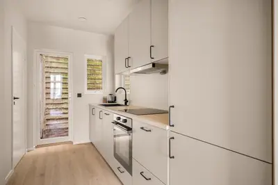 a white kitchen with white cabinets and a sink at City Apartment I Cozy with Perfect Location in Bergen