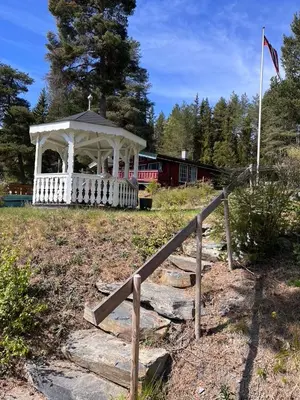 a white gazebo with a fence and a train at Glampingtelt i fjordkanten, Rønlund Hyttepark in Ron