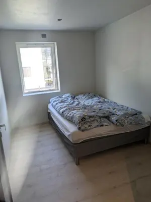 a bed in a white room with a window at Apartment in the middle of the city center in a quiet street in Stryn