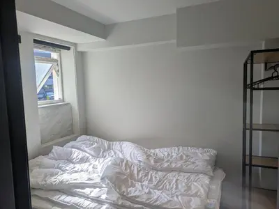 an unmade bed in a white room with a window at Apartment in the middle of the city center in a quiet street in Stryn
