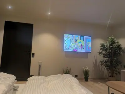 a bedroom with a bed and a tv on the wall at Apartment in the middle of the city center in a quiet street in Stryn