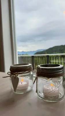 two glass jars with a candle in them on a table at Cabin by the lake with 3 bedrooms in Kvam