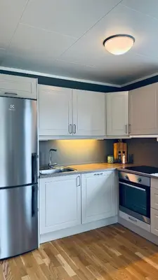 a kitchen with white cabinets and a stainless steel refrigerator at Cabin by the lake with 3 bedrooms in Kvam