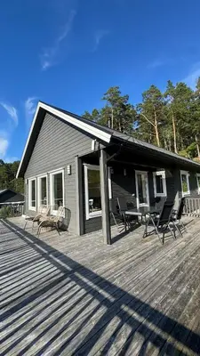 a large deck with chairs and a house at Cabin by the lake with 3 bedrooms in Kvam