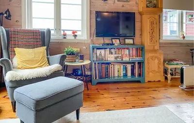 a living room with a tv and a chair and a book shelf at Stunning Home In Lavik in Lavik